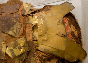 Nach dem Entfernen einiger Goldblätter wird eine goldene Maske mit einem Affenbild enthüllt.