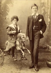 Junger Junge auf seinem Pferd als Dreirad, sein älterer Bruder daneben, 1880er Jahre