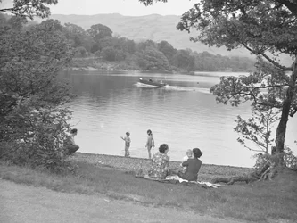 Eine Familie genießt sich neben einem See, Boot auf dem See, Hügel im Hintergrund