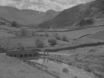 Blick über eine Brücke, Bach, Felder und Hügel