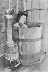 Das Bad ist ein großes Fass mit Kohlenofen. Häufig im Freien, um 1900, 1921