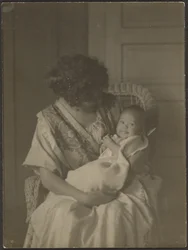 [Florence hält Baby im Schaukelstuhl]