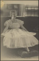[Frau im Chiffonkleid, auf einem Sofa sitzend]