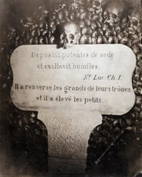 Die Beinhäuser der Katakomben von Paris. Peter trägt ein Zitat aus Kapitel 1 des Evangeliums von Lukas (Deposuit potentes de sede et exaltavit humiles. Auf Französisch: Er stürzte die Großen und erhob die Kleinen)