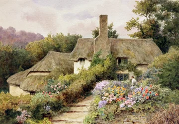 Ein Cottage in Selworthy, Somerset, England. Eine Frau im Garten eines englischen Landhauses.