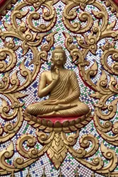 Eingangstür verziert mit Goldreliefs. Der lehrende Buddha zeigt einen besonderen Moment im Leben des Buddha, nämlich die erste Predigt nach der Erleuchtung