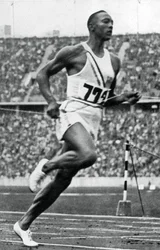 Jesse Owens am Ende des 100m-Laufs bei den Olympischen Spielen in Berlin, 1936