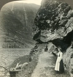 Wo die Straße unter den vorspringenden Klippen am Wasser des Nerofjords, Norwegen, ca. 1905, entlangkriecht