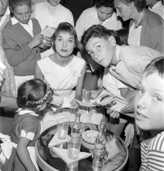 DIE SCHAUSPIELERIN UND DAS MODELL ELSA MARTINELLI BEI DEN XVIII. INTERNATIONALEN FILMFESTSPIELEN AM LIDO VON VENEDIG (sie gibt jungen Fans Autogramme. Auf dem Tisch steht eine Flasche Schweppes) - 1957