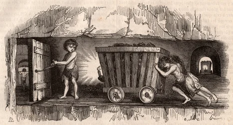 Zwei Kinder schieben einen Förderwagen in einem englischen Kohlebergwerk, ein drittes, der Schlepper, öffnet eine Tür