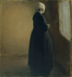 Eine alte Frau, die an einem Fenster steht