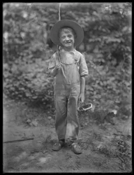 William Gray Hassler mit Strohhut und Latzhose, trägt Angelrute und Korb im Wald, 20. August 1911