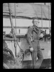 Ein nicht identifizierter Marineoffizier (?) steht an der Belegnagelbank auf der Backbordseite des Dreideckers HMS 